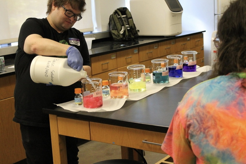 Dr. Andrew McShan (Assistant Professor, Chemistry & Biochemistry) prepares a rainbow with buffers and pH indicators. Photo Credit: Juliet Johnston