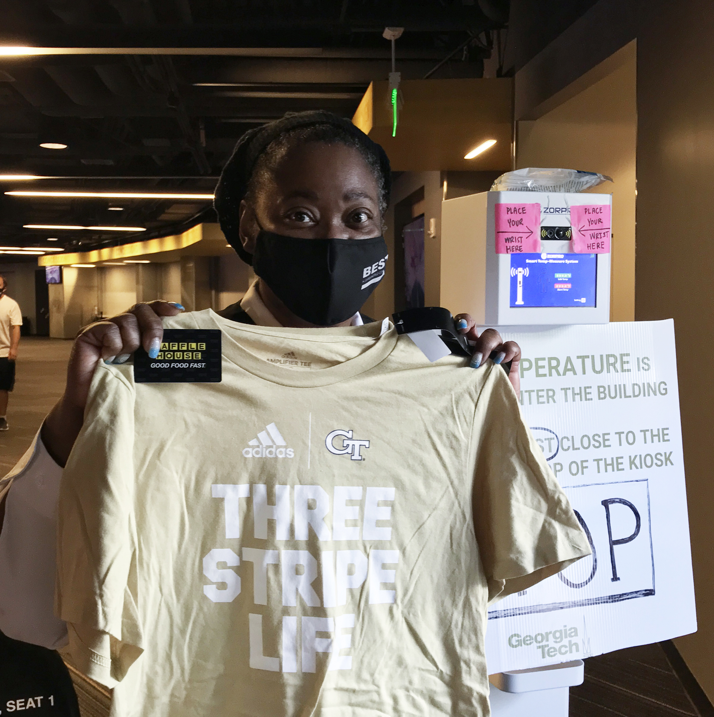Ms. Keresa, a staff member with Georgia Tech's Covid-19 campus vaccine clinic, holds one of the GT Athletics t-shirts and Waffle House discount cards handed out at a recent campus clinic.
