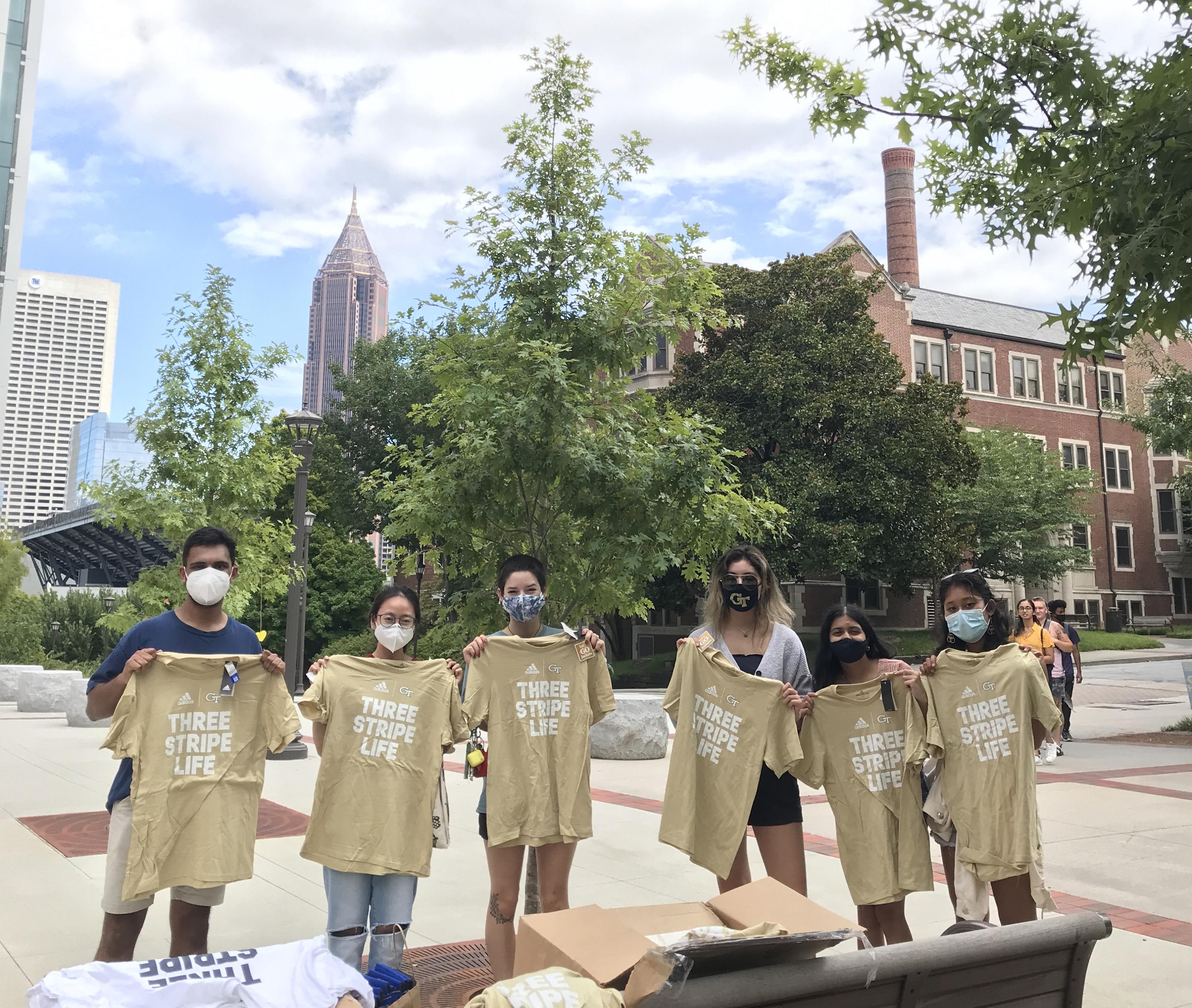 Mihir Kandarpa, vice president of Well-being for Undergrduate SGA (left) shares GT Athletics t-shirts and local restaurant discount cards with those participating in weekly asymptomatic surveillance testing at Georgia Tech.