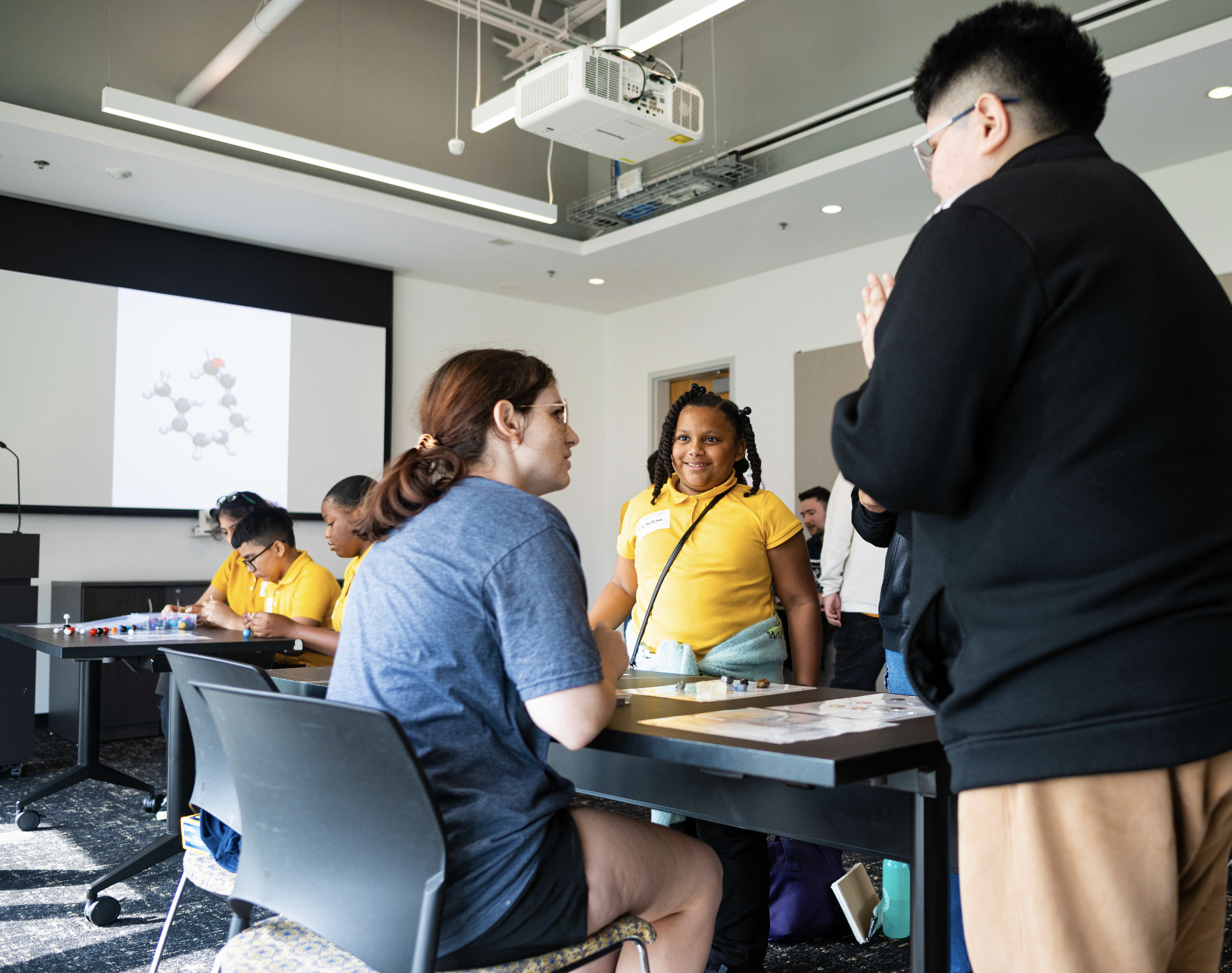 Middle school and graduate students discussing computational and physical molecular models.